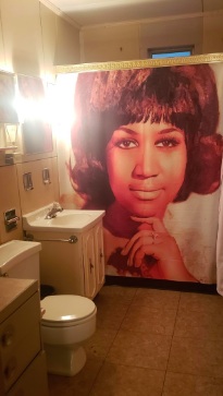 A photo of the bathroom including a shower curtain with a photo of Aretha Franklin on it